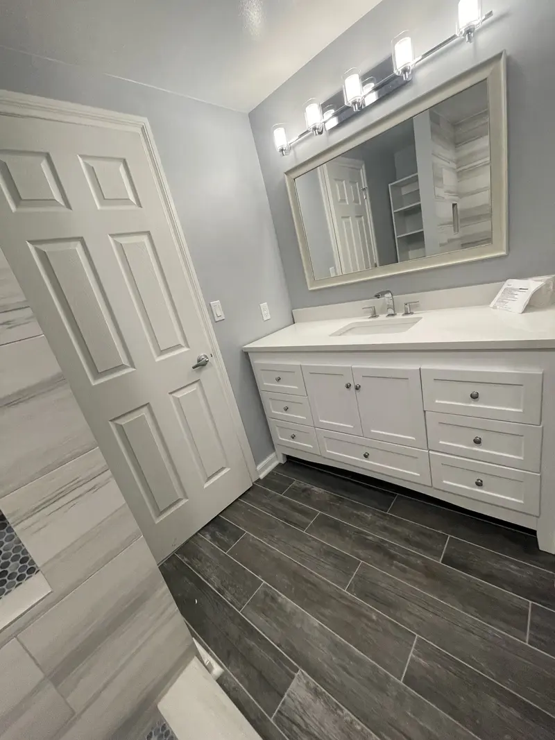 View from the doorway over the plank tile floor to the vanity and mirror