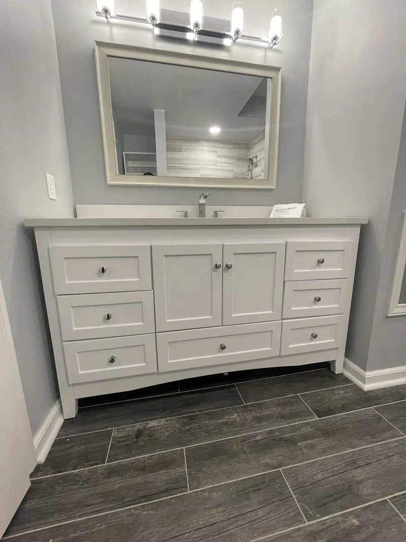 Front view of the white shaker vanity with drawers, a single sink and a framed mirror