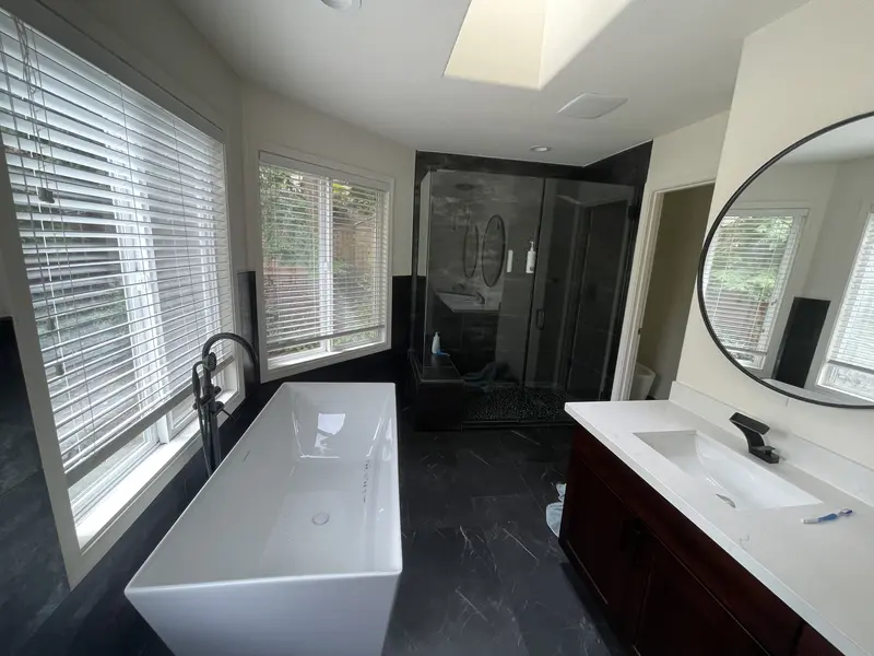 View from the tub across the bathroom to the glass shower under the skylight, with the vanity on the right