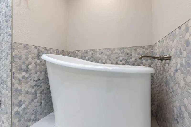 Freestanding soaking tub against a blue-gray hex mosaic wainscot, video thumbnail