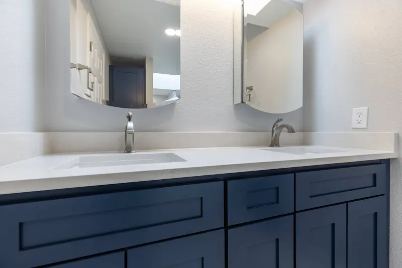 Navy shaker double vanity with white tops and two rounded mirrors