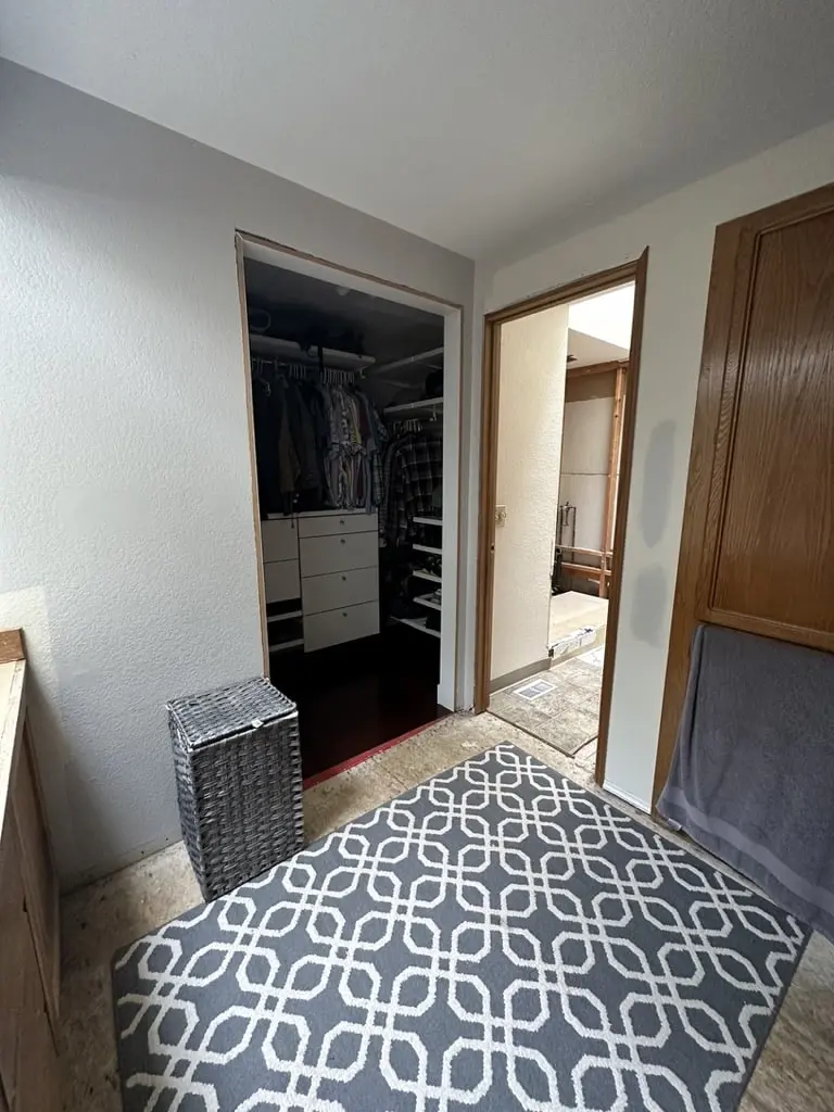 Old bathroom floor with a patterned rug and the doorway into the closet