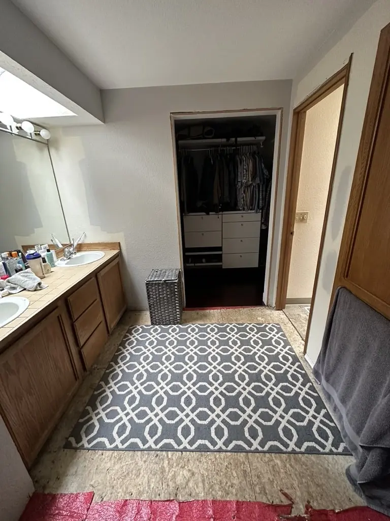 Old wood vanity run leading toward a walk-in closet, with a patterned rug on the floor