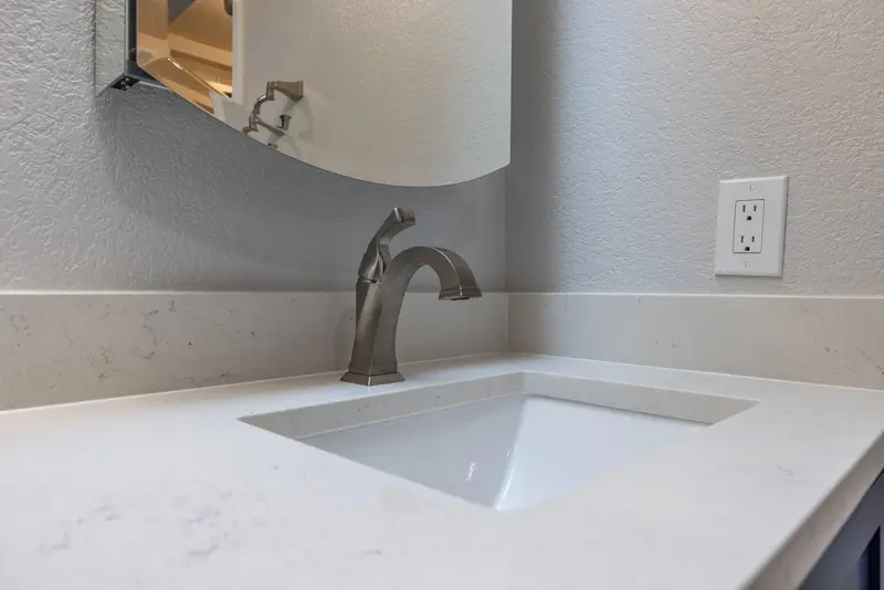 Undermount sink in a white top with a brushed bronze faucet