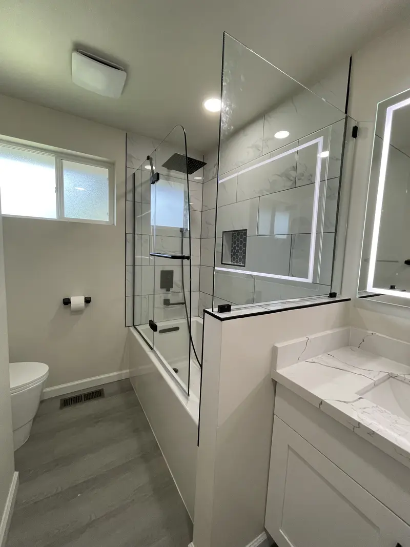 View of the vanity, glass panel and tub from the doorway