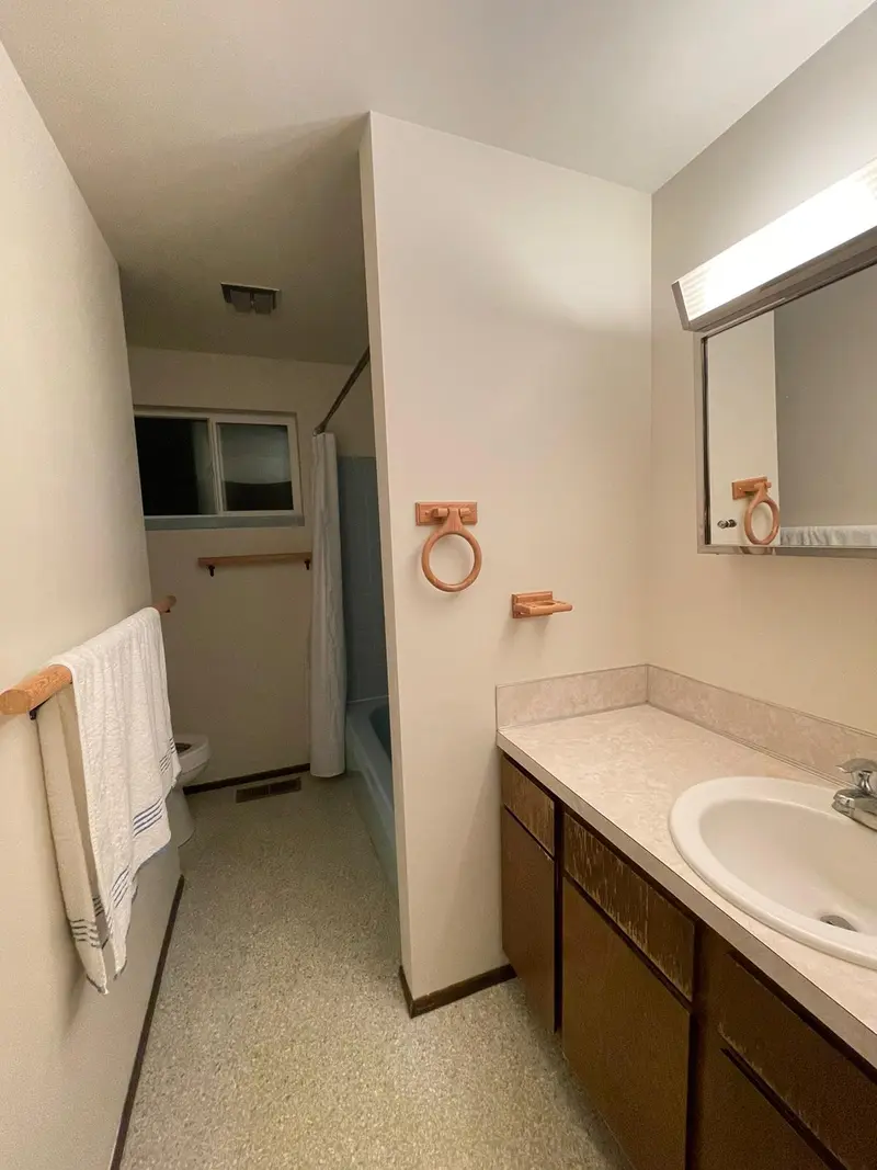 Original bathroom with a dark wood vanity, laminate counter and a long mirror cabinet