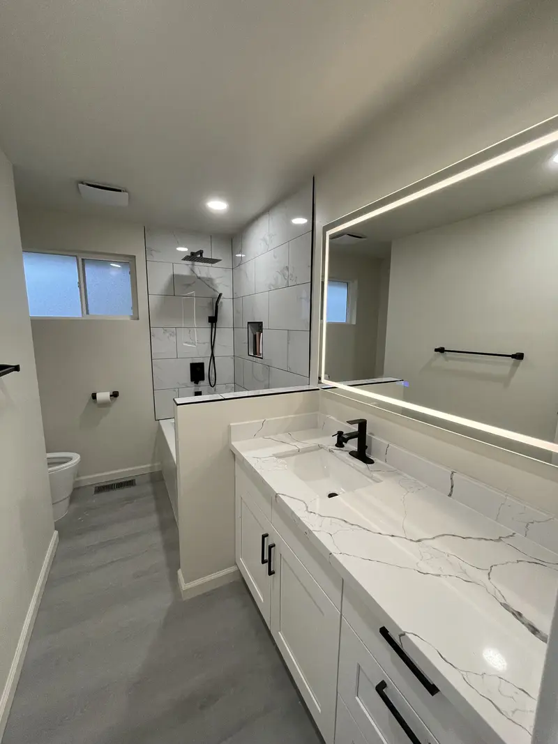 Long vanity with a lit mirror running above it and a window at the far end