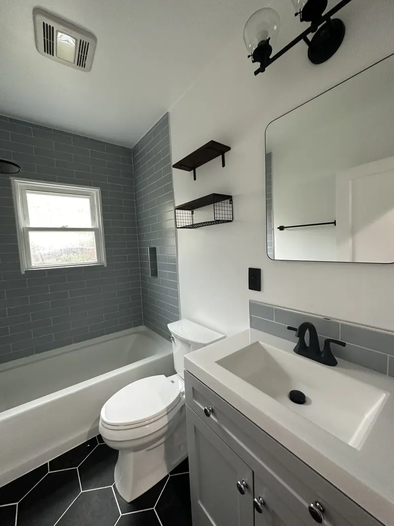Bathroom with a gray vanity, white integrated sink, black faucet, mirror and black wall shelf
