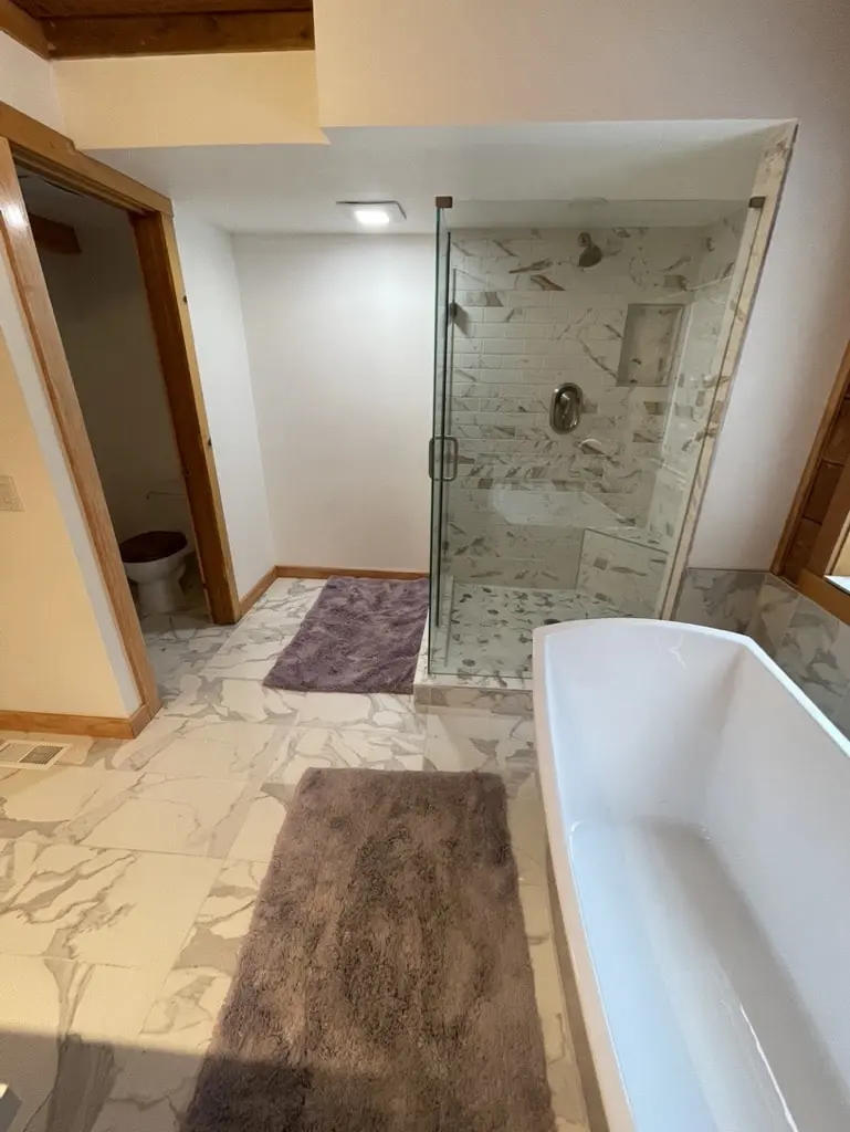 Frameless glass shower with a tiled niche and a separate toilet room door