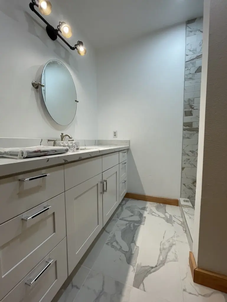 Gray shaker vanity drawers under a veined counter on a marble-look floor