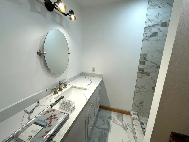 Marble-look vanity counter with an undermount sink and a faucet, seen from beside the shower opening