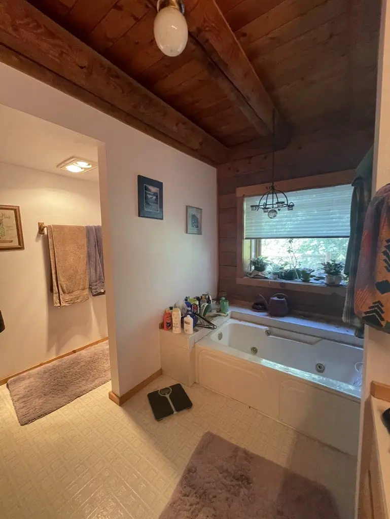 Jetted tub deck under a window with log walls and a cedar ceiling before the remodel