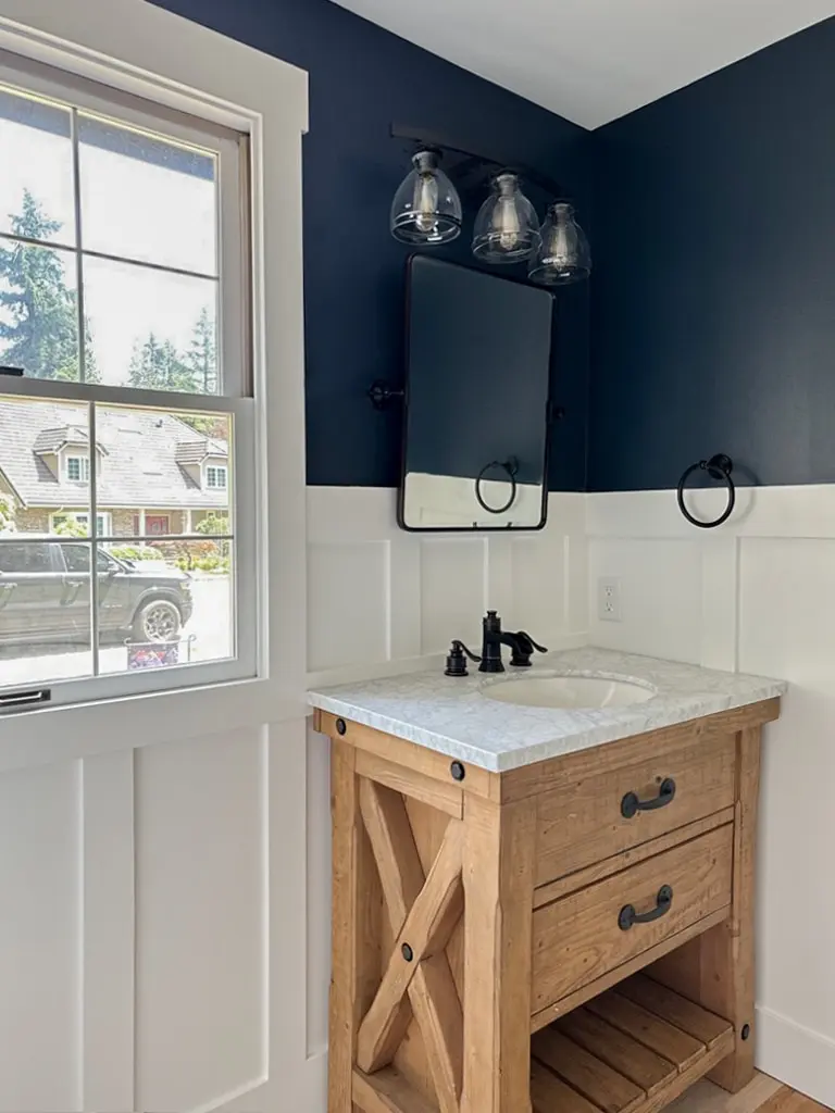 Vanity beside a white trimmed window under a three-globe glass light fixture