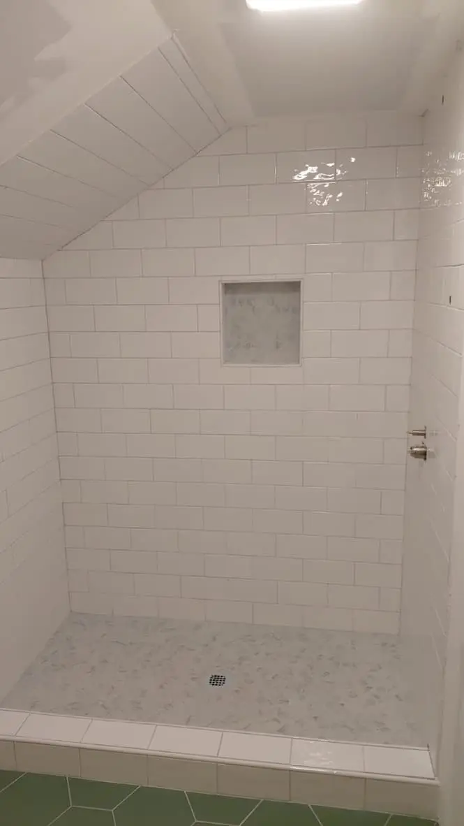 Tiled shower with a marble-look mosaic niche, low curb and mosaic floor