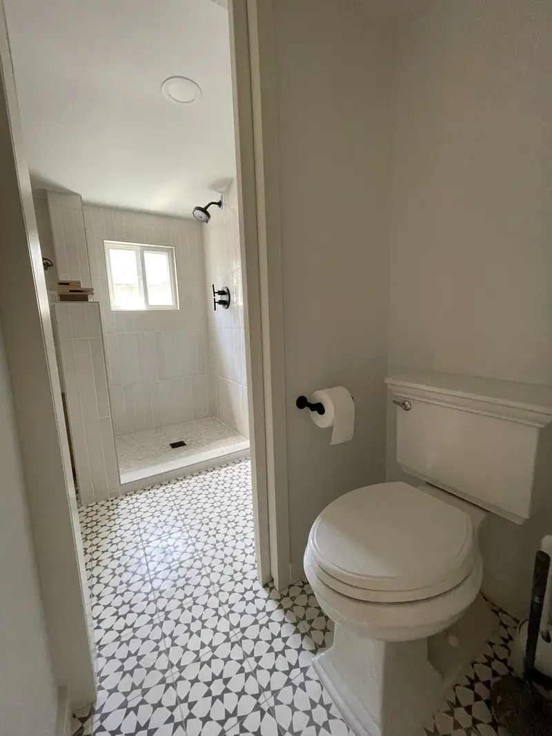 Toilet in a side nook with the star tile floor running through to the shower