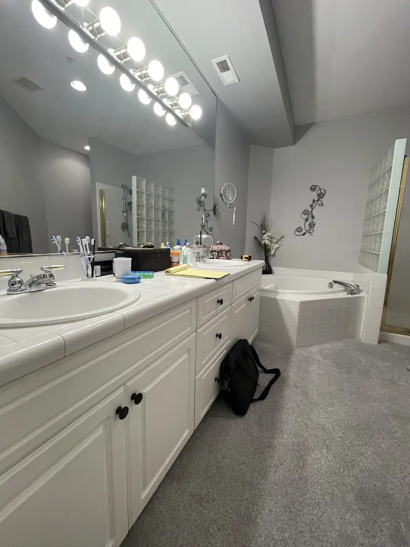 Original long vanity with a row of globe lights and the tub beyond