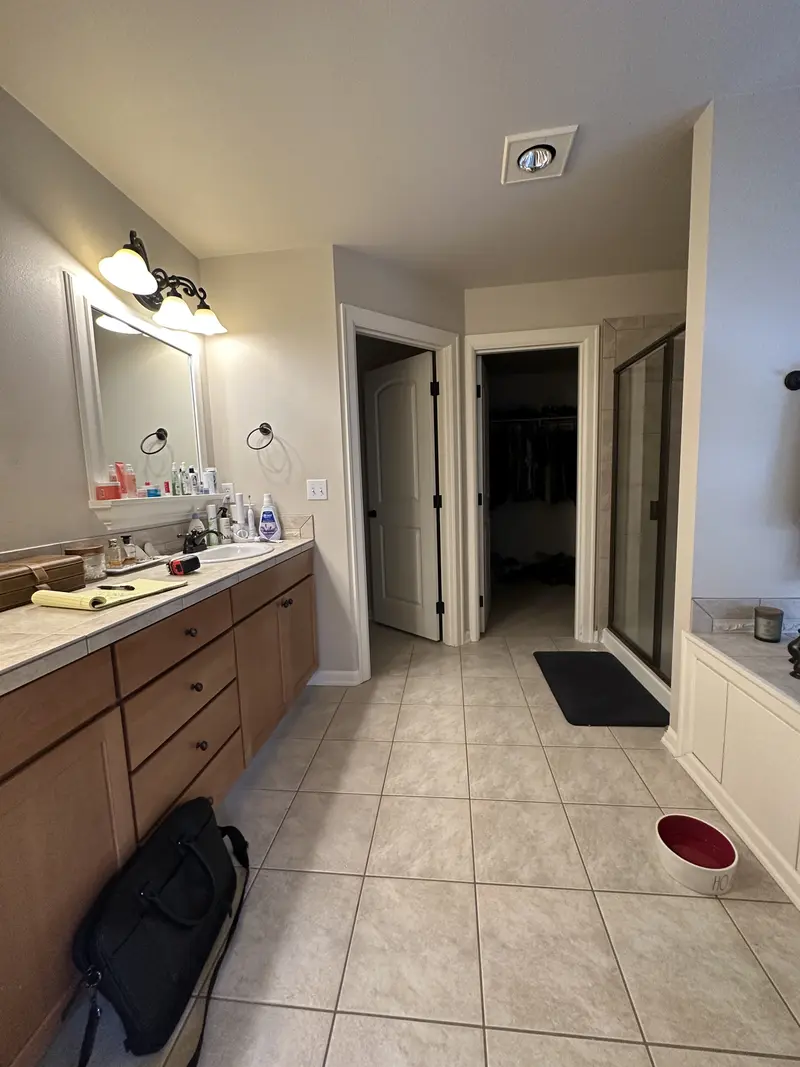 Long view of the old oak double vanity and beige tile floor toward the closet doors