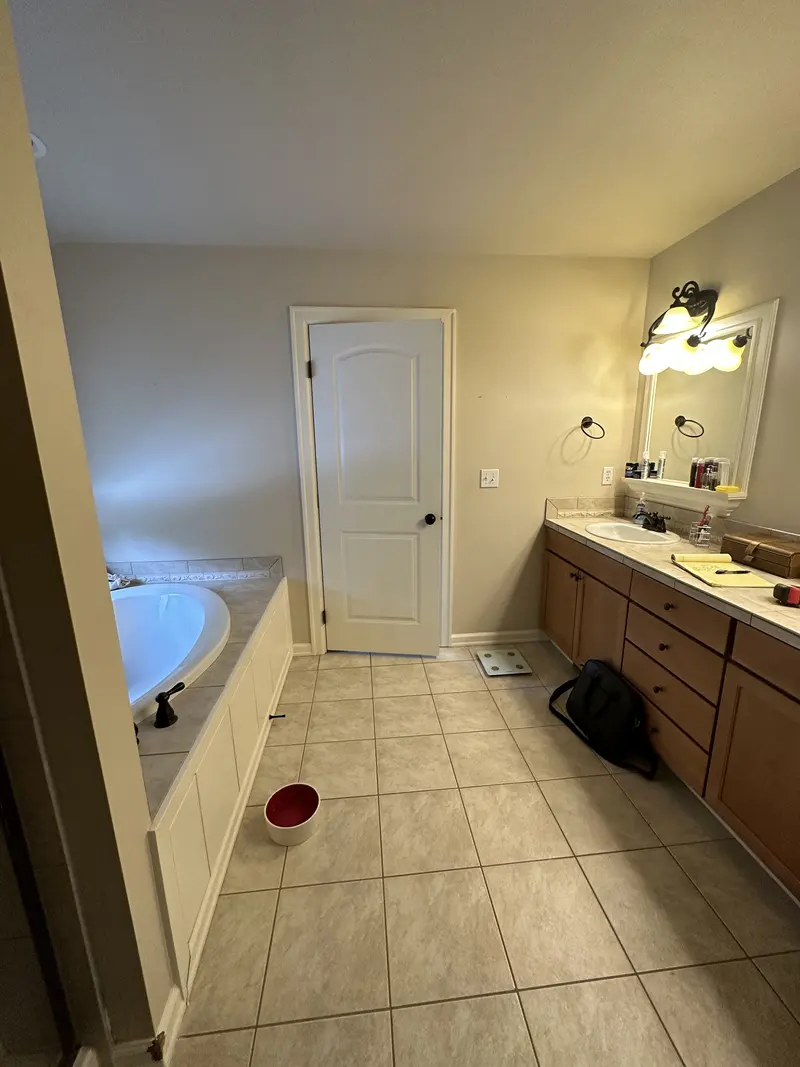 Before the remodel: tub deck on one side, an oak vanity on the other and beige floor tile