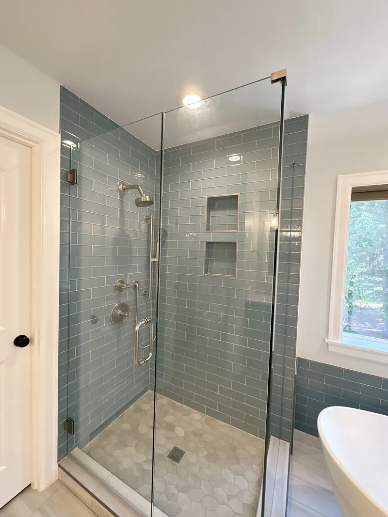 Frameless glass shower seen from the door side with stacked niches and a hexagon tile floor