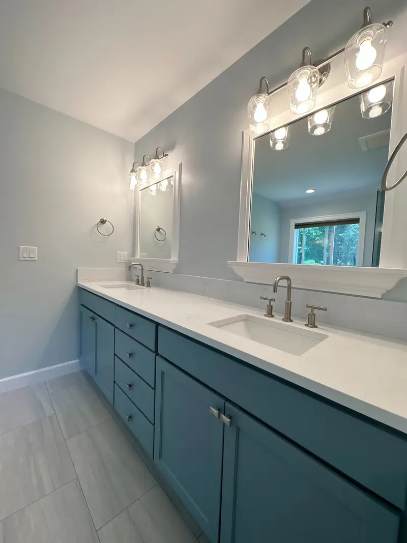 Long teal shaker double vanity with a white counter, two sinks and two framed mirrors