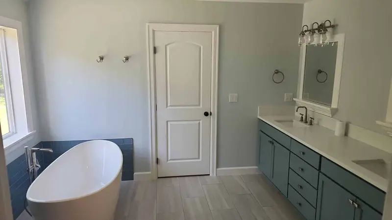 Wide view of the remodeled bathroom from the tub to the door and the teal vanity