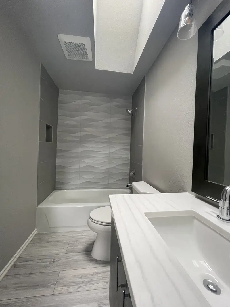 White vanity top with an undermount sink and chrome faucet, the tub beyond