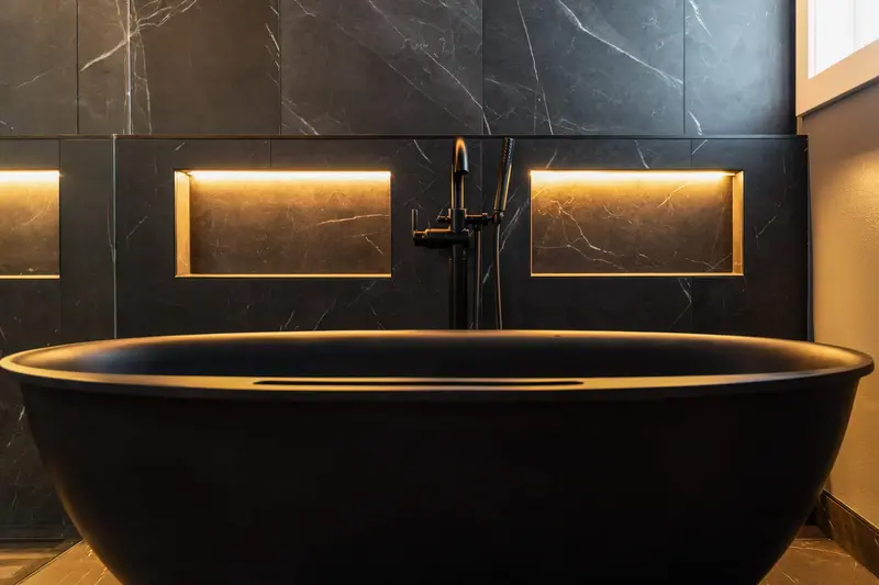 Black freestanding tub with a matte black floor-mounted faucet and warm lit niches behind it