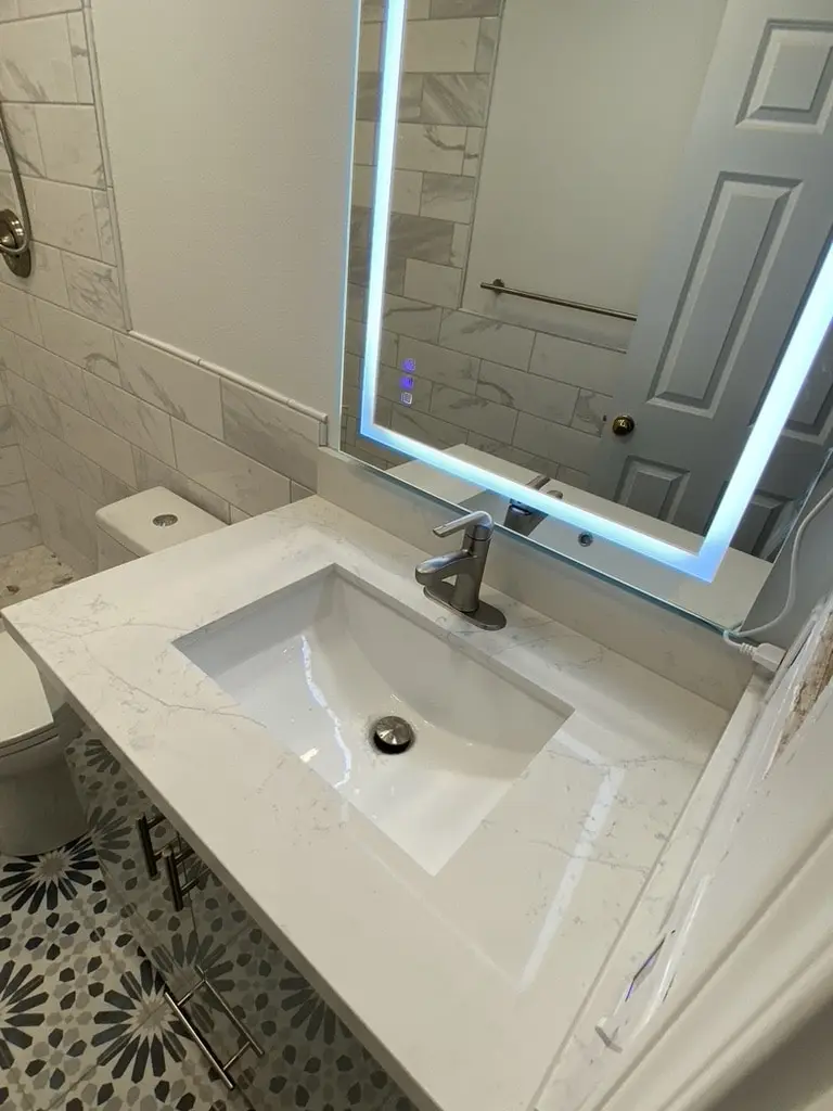 White quartz-look counter with an undermount sink and brushed nickel faucet over the patterned floor