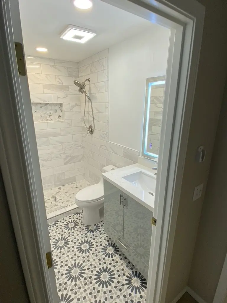 Doorway view of the shower, toilet and vanity in the compact bathroom