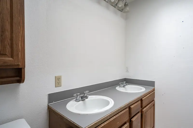 Gray laminate counter with two drop-in sinks on an oak vanity, before the remodel