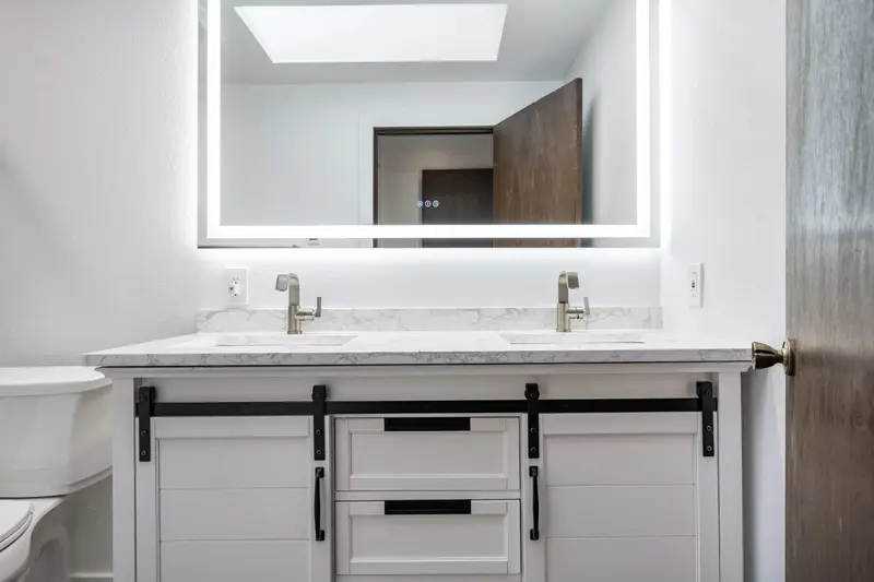White double vanity with sliding barn-style doors, black hardware and a marble-look counter