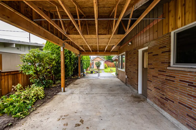 Long view under the new carport along the brick wall toward a back gate