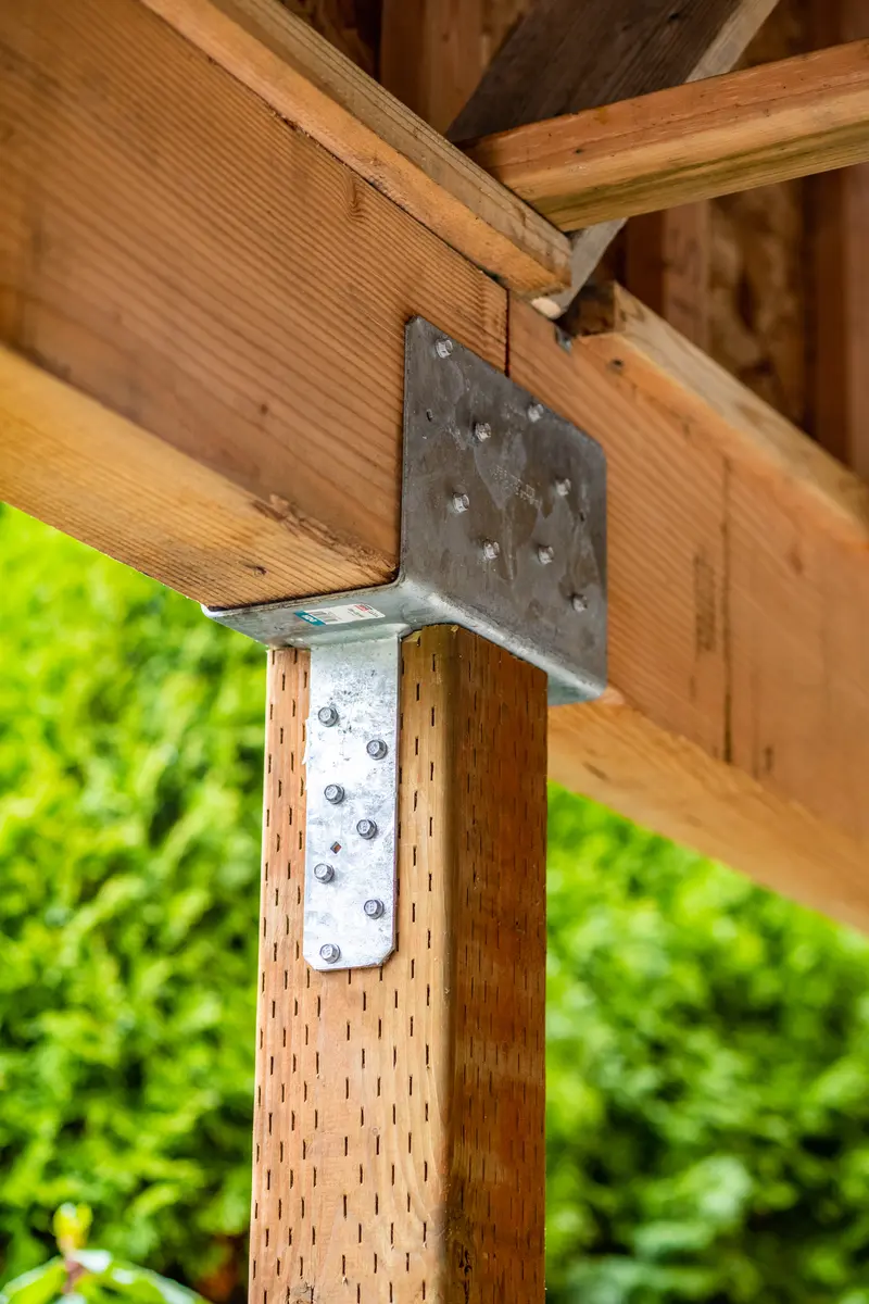 Wood carport post joined to a beam with a galvanized steel connector plate