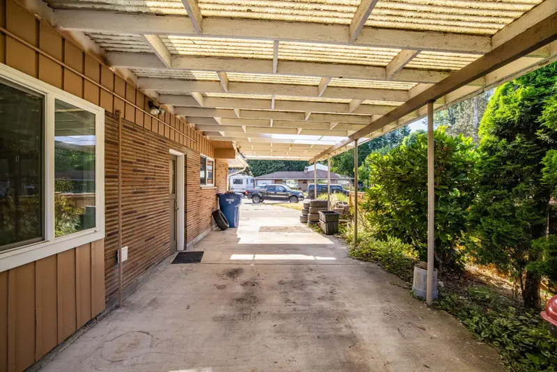 Long old carport along the side of a brick house, looking toward the street