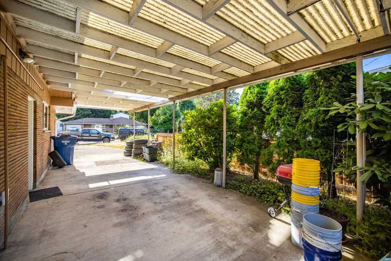 Underside of the old carport with translucent panels and thin posts along the house