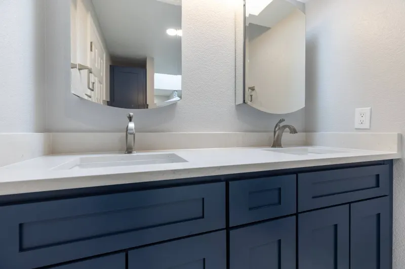 Navy shaker double vanity with a white quartz top, two undermount sinks and arched mirrors, from a Redmond bathroom remodel by Volcano Builders