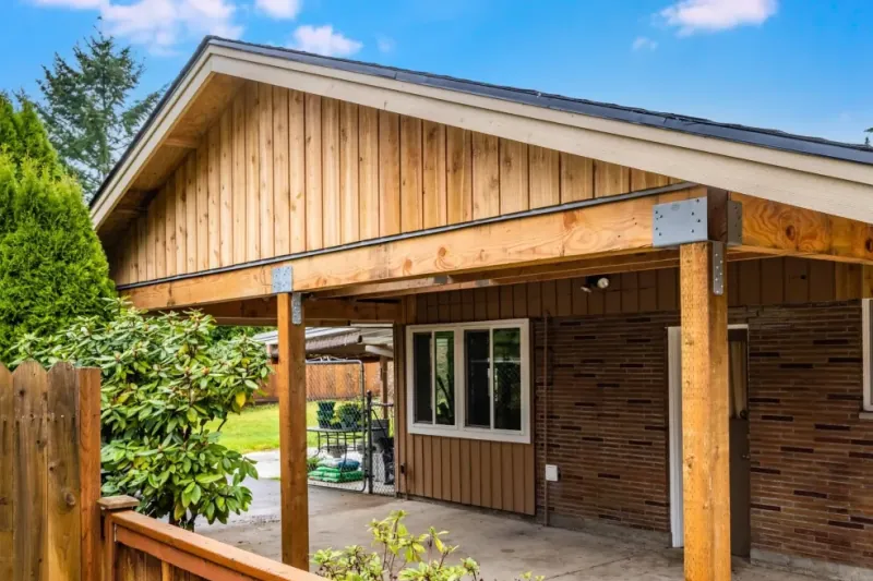 New gable roof carport with cedar posts and board siding on an Auburn home, built by Volcano Builders