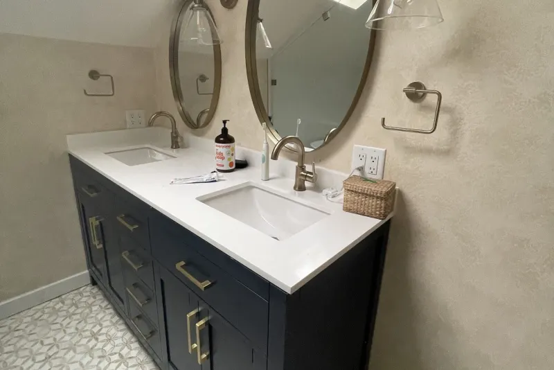 Navy double vanity with brass pulls and round mirrors in a Seattle primary bathroom remodeled by Volcano Builders