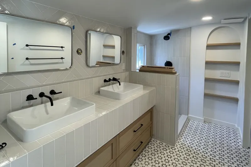 Double vanity with vessel sinks, black wall faucets and patterned floor tile in a Seattle bathroom remodel by Volcano Builders