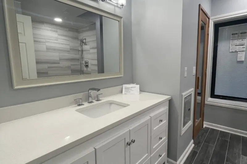 White shaker vanity with a quartz top and framed mirror in a Federal Way basement bathroom remodel by Volcano Builders