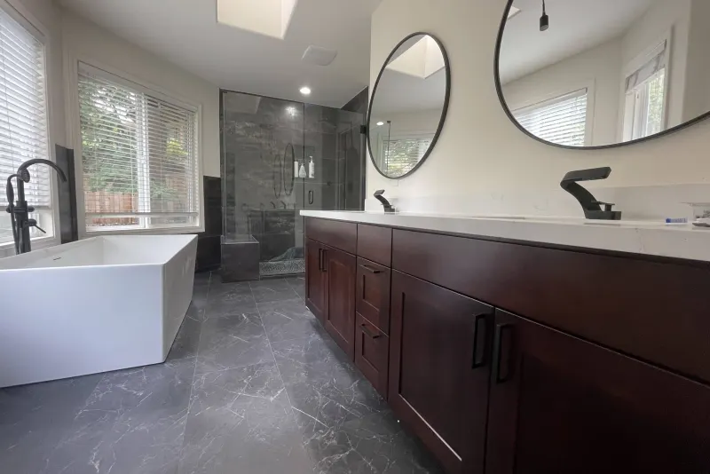 Remodeled primary bathroom in Issaquah with a freestanding tub, dark wood double vanity and glass walk-in shower