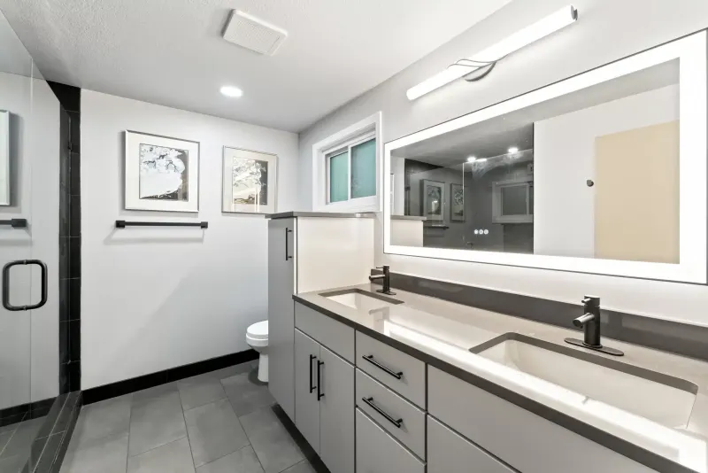 Bathroom remodel in Kirkland by Volcano Builders, gray double vanity with a lit mirror and black fixtures