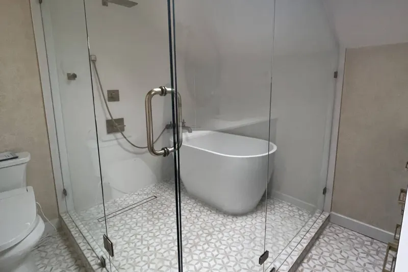 Frameless glass shower enclosing a freestanding tub under a skylight, with star pattern floor tile, from a Seattle bathroom remodel by Volcano Builders