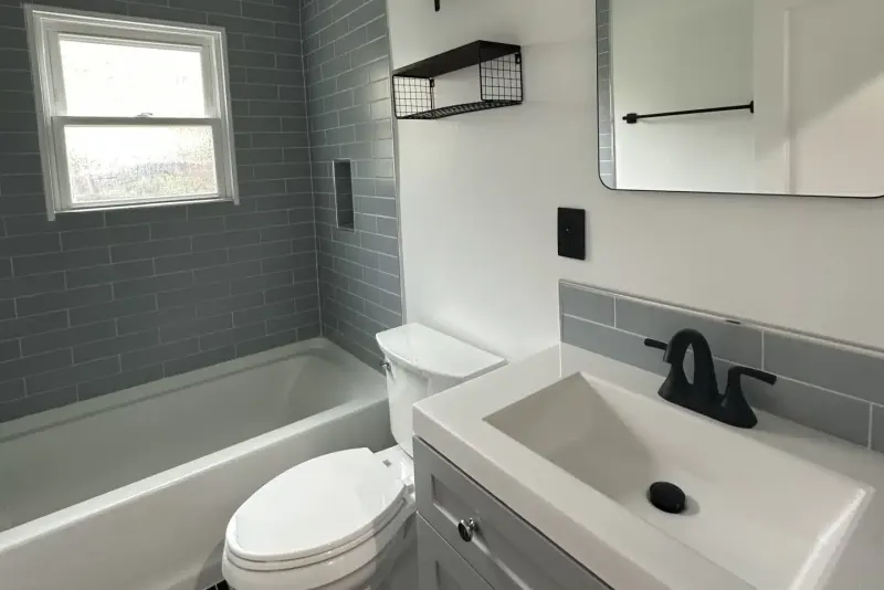Remodeled bathroom with gray subway tile, a soaking tub and a black faucet on a white vanity, a Seattle project by Volcano Builders