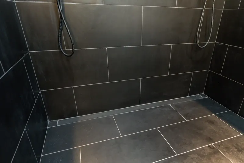 Curbless walk-in shower with charcoal large format tile and a linear drain, from a Kirkland bathroom remodel by Volcano Builders