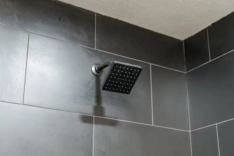 Matte black square rain shower head on charcoal large format wall tile, from a Kirkland bathroom remodel by Volcano Builders