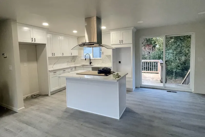 Kitchen with a white island and stone counters from a Renton whole home remodel by Volcano Builders