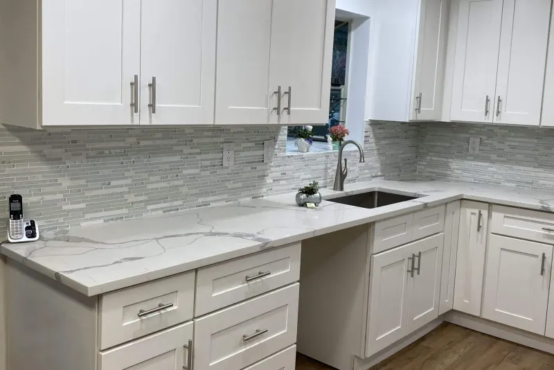 White shaker cabinets, quartz counters and a glass mosaic backsplash in a Snohomish kitchen remodel by Volcano Builders