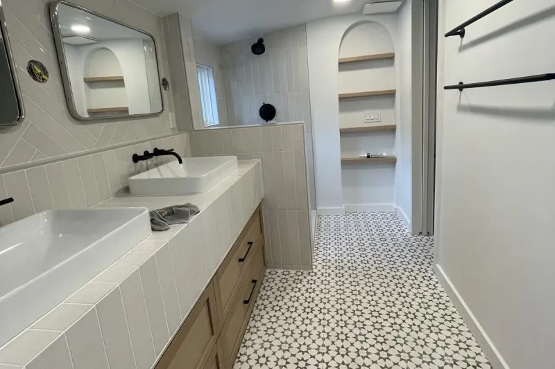 Long double vanity with two vessel sinks, patterned cement tile floor and arched open shelves, from a Seattle bathroom remodel by Volcano Builders