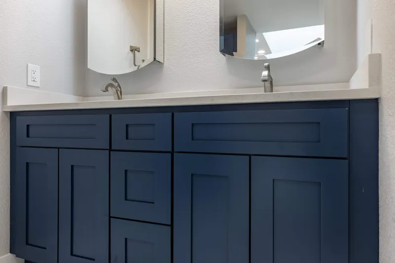 Navy shaker double vanity with a white quartz top and brushed nickel faucets, from a Redmond bathroom remodel by Volcano Builders